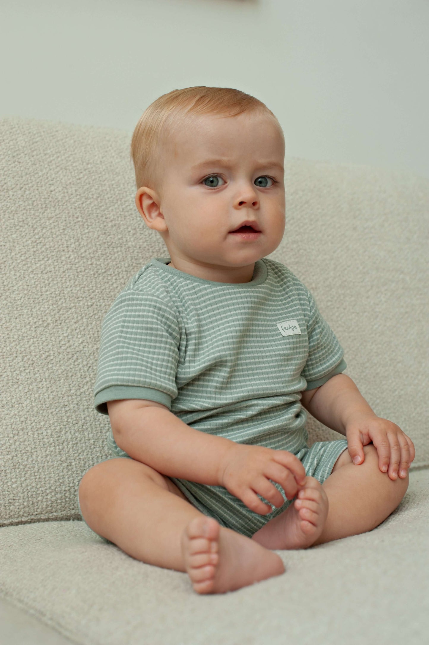 Feetje shortama zeegroene kleur voor jongens en meisjes, afbeelding van een kind in een zachte pyjama.