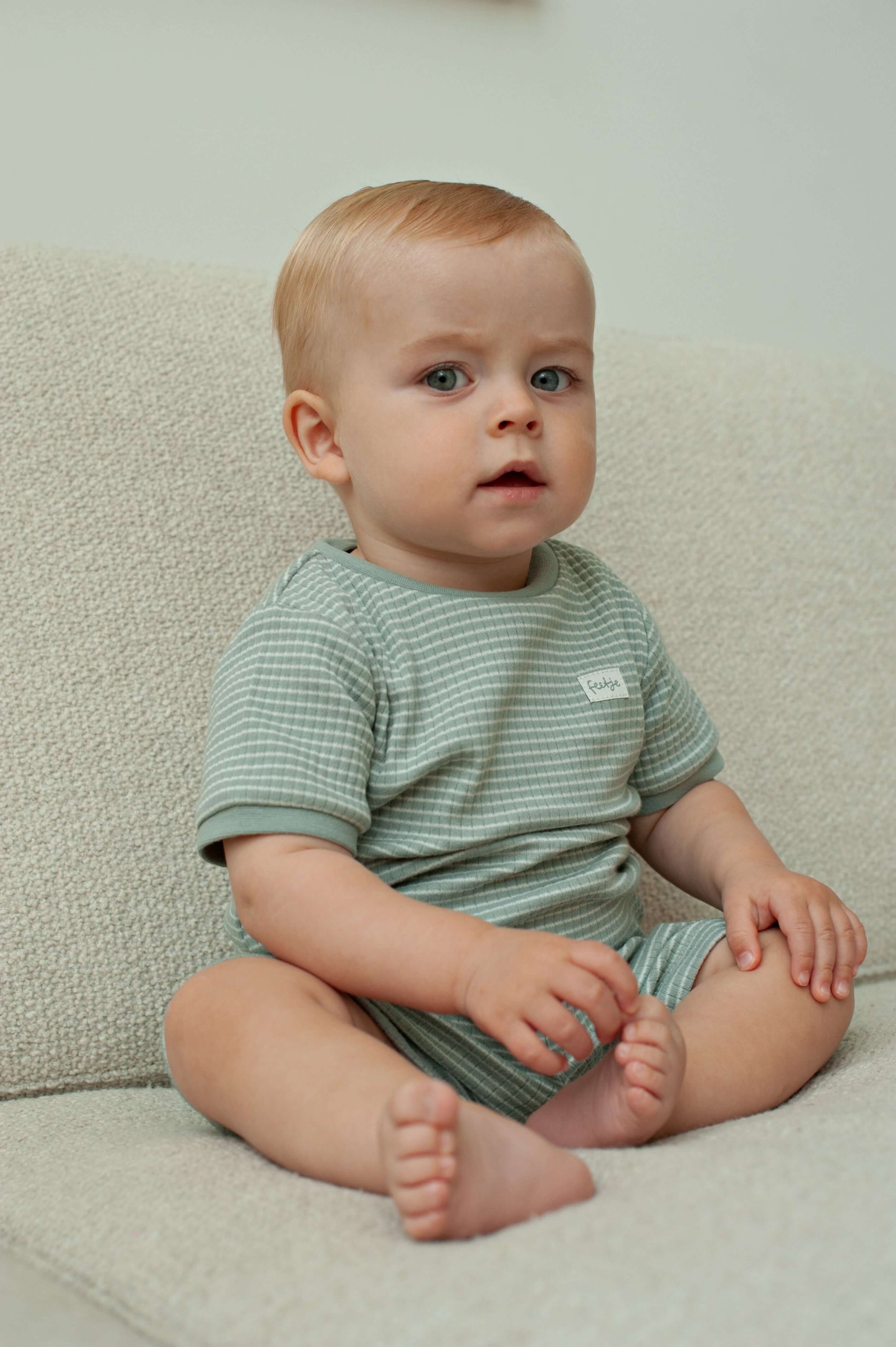 Feetje shortama zeegroene kleur voor jongens en meisjes, afbeelding van een kind in een zachte pyjama.